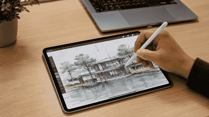 Person using Apple Pencil on iPad Pro for creative design work at a home office desk