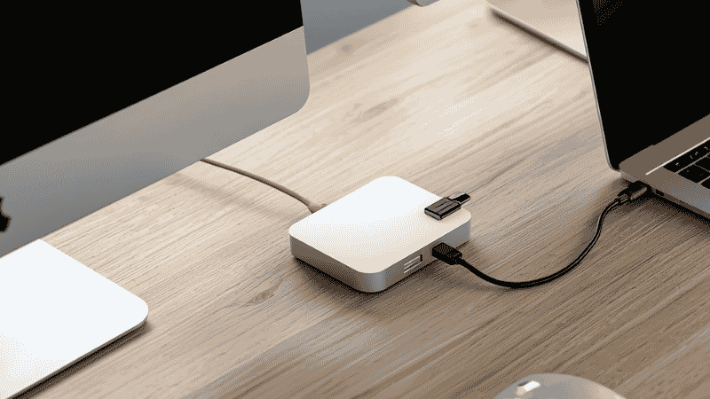 A Thunderbolt docking station on a clean home office desk connecting a laptop to dual monitors, keyboard, and mouse with a single cable
