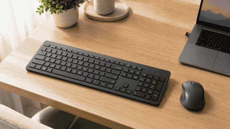 Wireless keyboard and mouse combo on a clean home office desk with USB receiver and minimal cable clutter