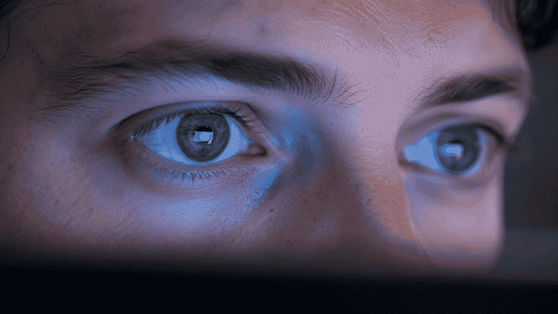 Close-up of a person's eyes staring intently at a computer screen showing reduced blinking during screen focus
